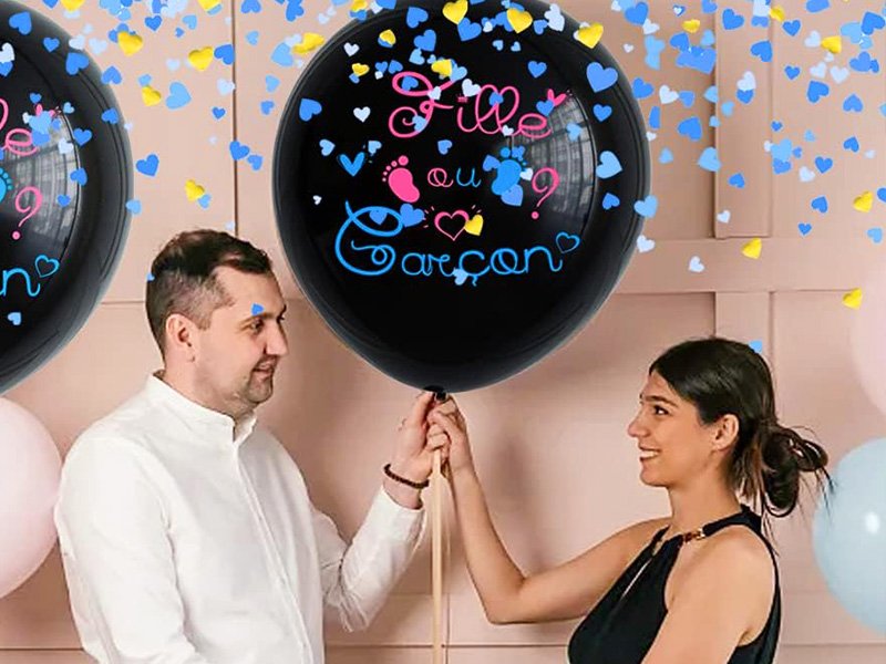 Futurs parents tenant un ballon géant noir de gender reveal rempli de confettis