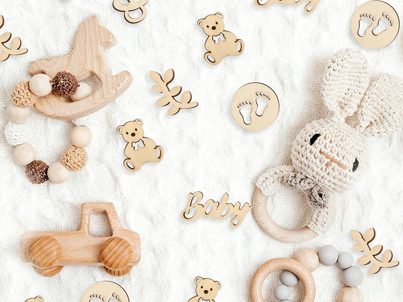 Confettis en bois en forme d’ourson, de tétine, de lapin et de lettres Baby posés sur une table