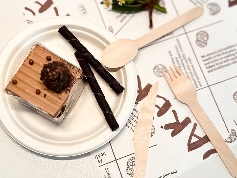 Couverts jetables en bois posés sur une assiette avec une part de gâteau