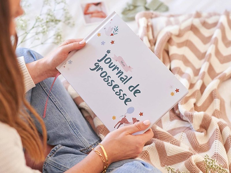 Femme enceinte tenant un journal de grossesse à remplir