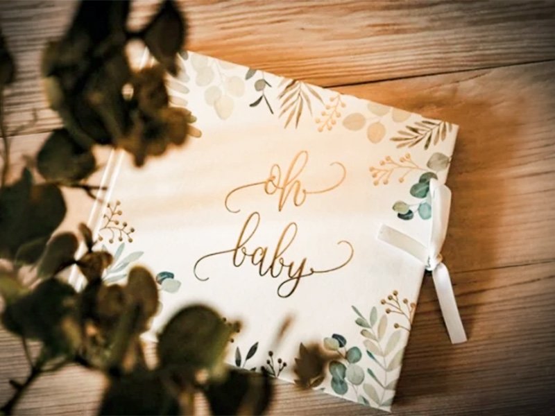 Livre d’or Oh Baby à couverture eucalyptus et dorée entouré de feuillage