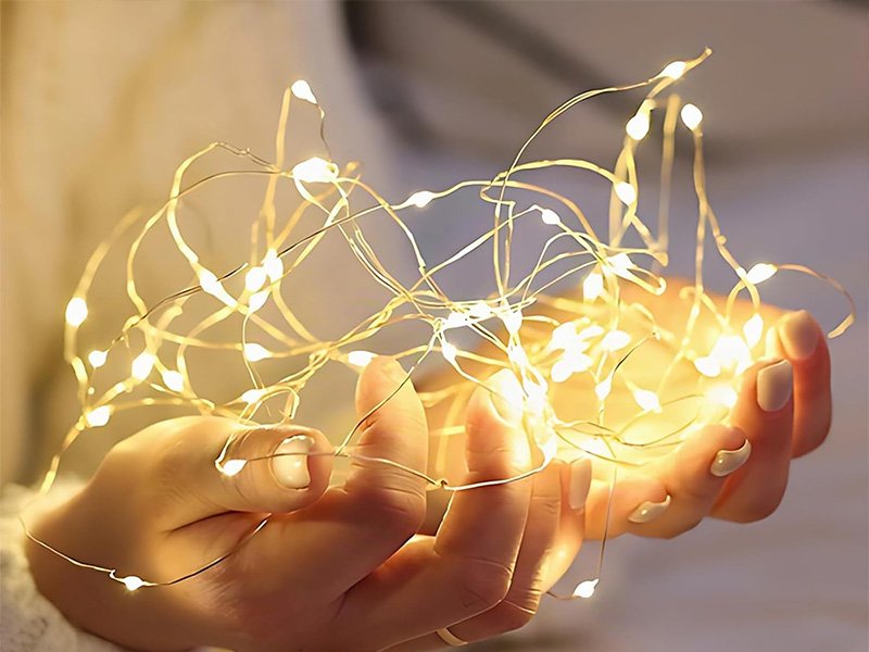 Mini guirlande lumineuse LED à piles tenue dans une main, lumière chaude