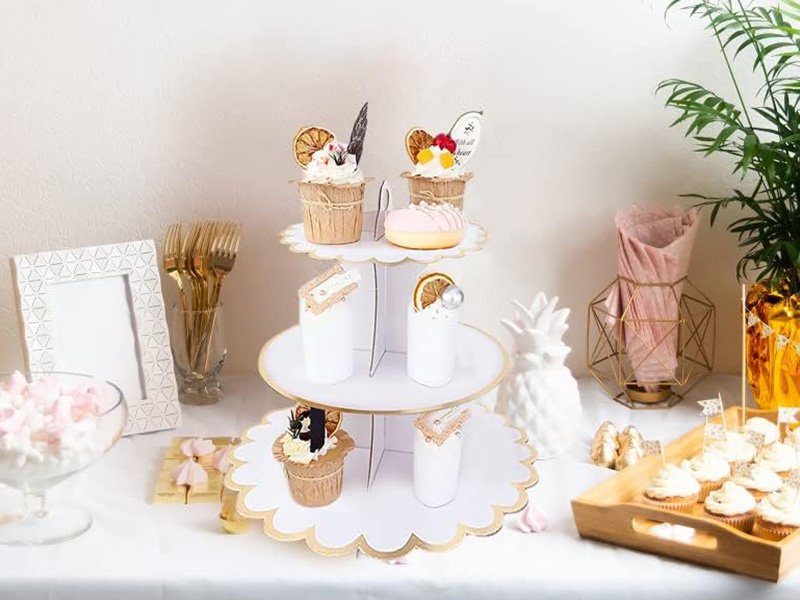 Présentoir à gâteaux blanc à 3 étages garni de cupcakes sur une table de fête